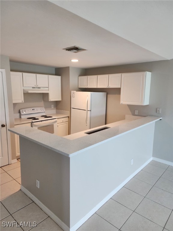 kitchen with kitchen peninsula, light tile patterned floors, white cabinets, and white appliances