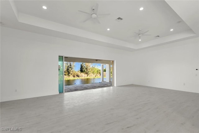 spare room with a tray ceiling, visible vents, and ceiling fan