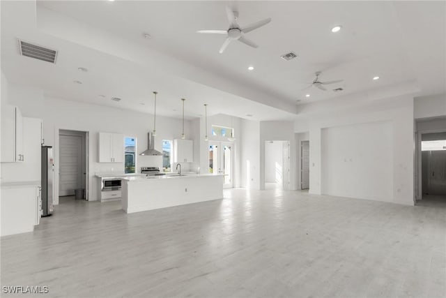 unfurnished living room with light wood-style floors, ceiling fan, visible vents, and a sink