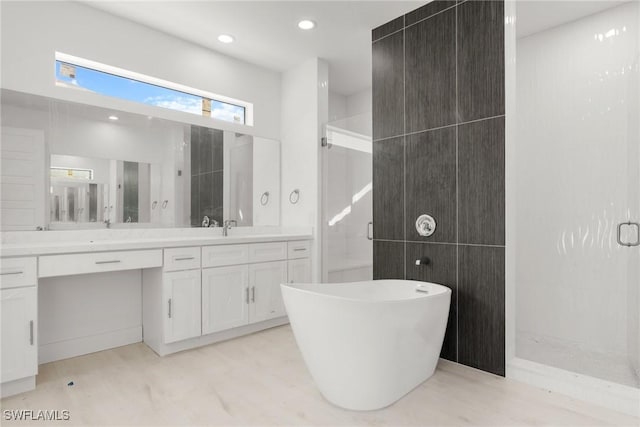 bathroom with a stall shower, recessed lighting, a freestanding bath, and vanity