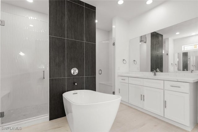 full bath featuring a freestanding bath, a stall shower, vanity, and tile walls