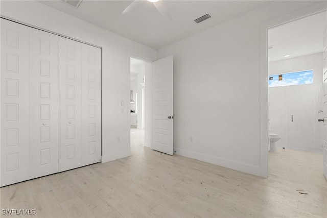 unfurnished bedroom featuring light wood finished floors, connected bathroom, visible vents, and a closet