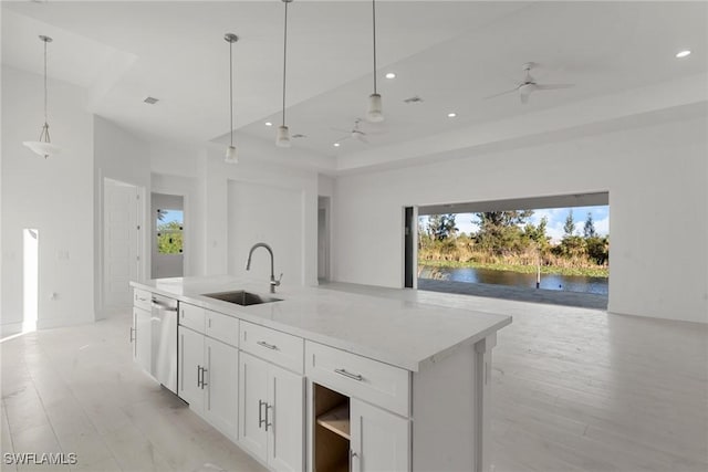 kitchen featuring a water view, stainless steel dishwasher, open floor plan, and a sink