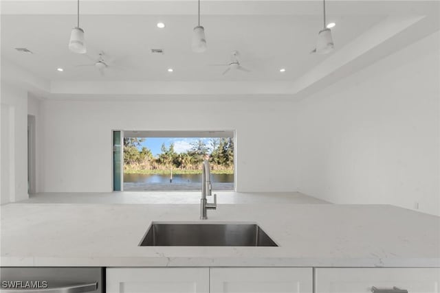 kitchen featuring hanging light fixtures, a sink, white cabinetry, and light stone counters