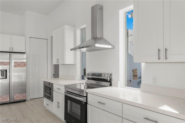 kitchen featuring white cabinets, light wood-style flooring, light stone counters, built in appliances, and exhaust hood