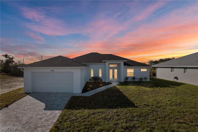 view of front facade with decorative driveway, a yard, an attached garage, and stucco siding