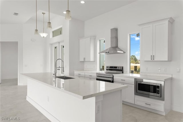 kitchen featuring a kitchen island with sink, sink, stainless steel appliances, and wall chimney range hood