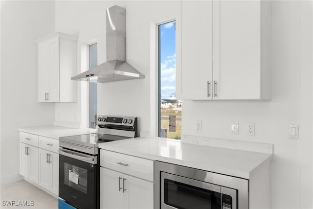 kitchen with wall chimney exhaust hood, white cabinetry, and stainless steel appliances