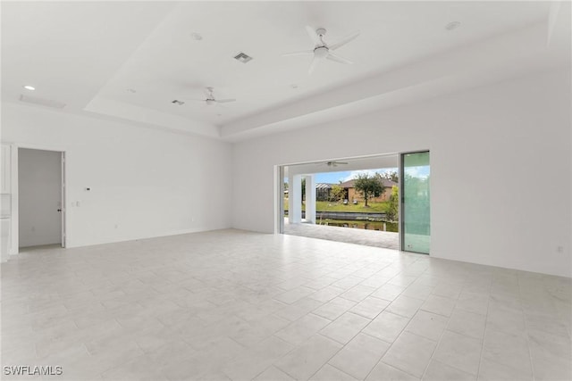 spare room with a tray ceiling, visible vents, and a ceiling fan