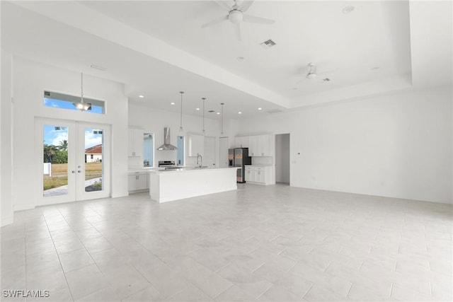 unfurnished living room featuring ceiling fan, light tile patterned floors, sink, and french doors