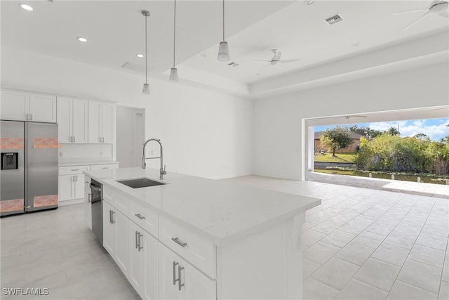 kitchen featuring stainless steel appliances, white cabinetry, a center island with sink, and hanging light fixtures