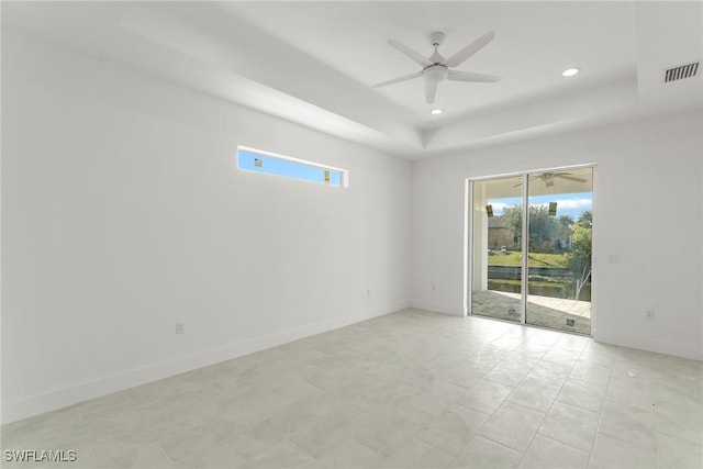 unfurnished room with ceiling fan and a raised ceiling