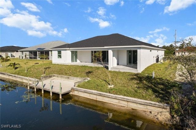 back of house featuring a patio, a water view, and a lawn