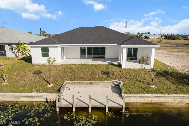 rear view of property with a yard, a patio, and a water view