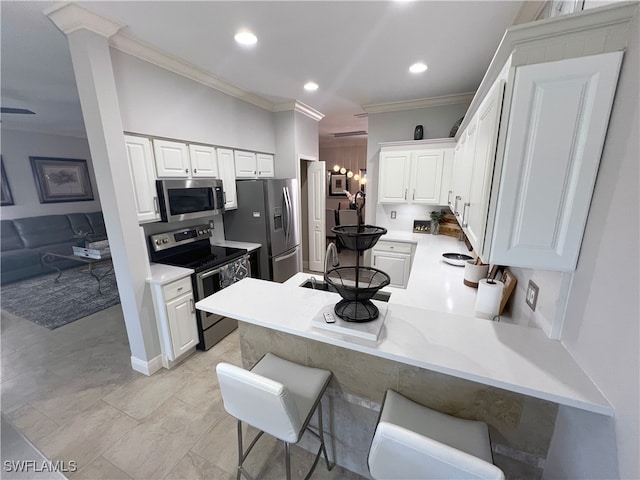 kitchen with a breakfast bar area, appliances with stainless steel finishes, white cabinetry, ornamental molding, and kitchen peninsula