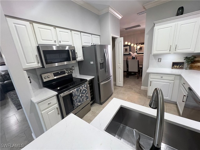 kitchen featuring sink, white cabinetry, crown molding, light tile patterned floors, and stainless steel appliances