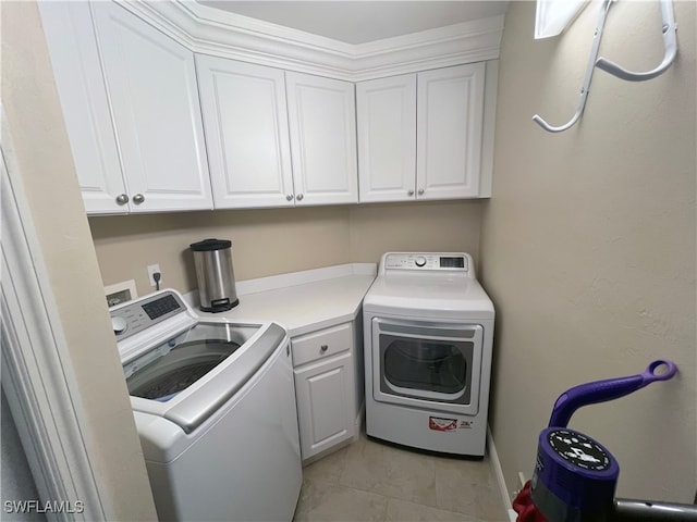 laundry area with cabinets, washer and dryer, and light tile patterned floors