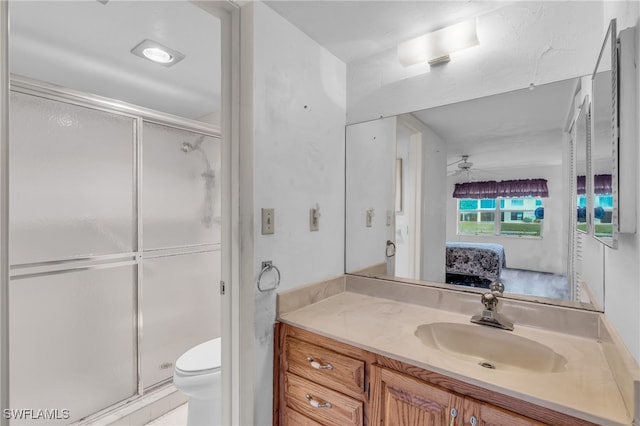 bathroom featuring ceiling fan, vanity, an enclosed shower, and toilet