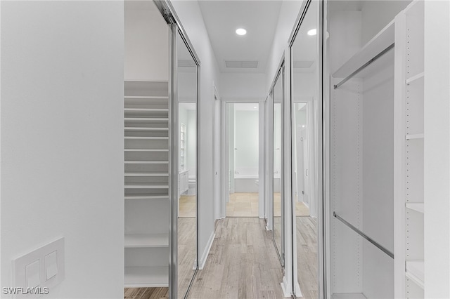 walk in closet with light hardwood / wood-style floors