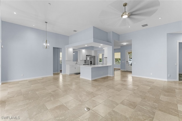 kitchen with white cabinets, ceiling fan with notable chandelier, sink, hanging light fixtures, and stainless steel refrigerator with ice dispenser