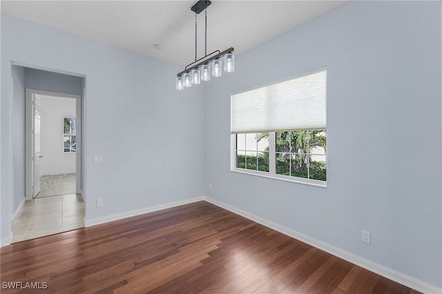 spare room featuring light wood-type flooring and an inviting chandelier