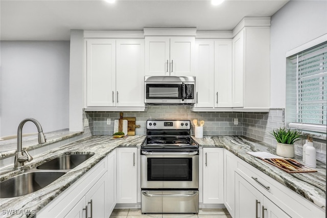 kitchen with white cabinets, sink, decorative backsplash, appliances with stainless steel finishes, and light stone counters