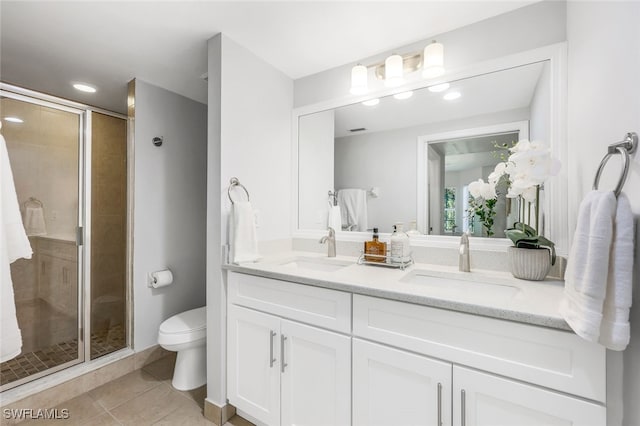 bathroom featuring toilet, vanity, tile patterned floors, and an enclosed shower