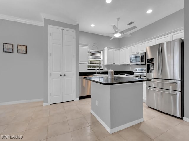 kitchen with white cabinetry, a center island, crown molding, light tile patterned floors, and appliances with stainless steel finishes