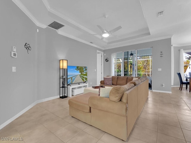 living room with a tray ceiling, ceiling fan, ornamental molding, and light tile patterned flooring