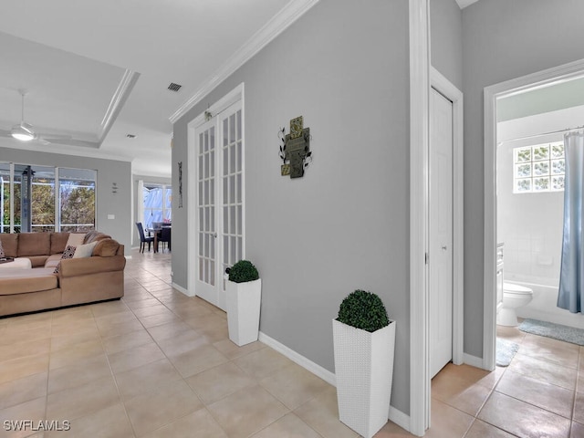 corridor with crown molding, plenty of natural light, light tile patterned floors, and french doors