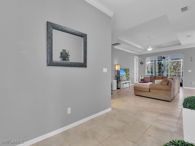 living room with a tray ceiling, ceiling fan, light tile patterned floors, and ornamental molding