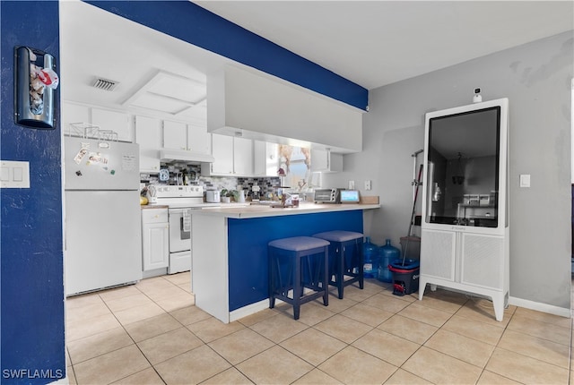 kitchen with white appliances, decorative backsplash, white cabinetry, kitchen peninsula, and a breakfast bar area