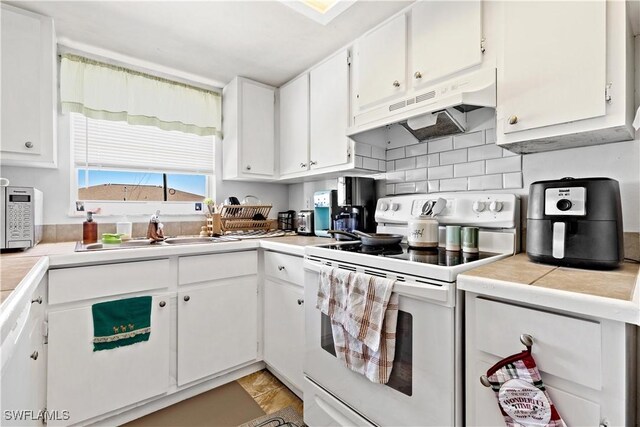 kitchen featuring white cabinetry, sink, backsplash, white range with electric cooktop, and tile countertops