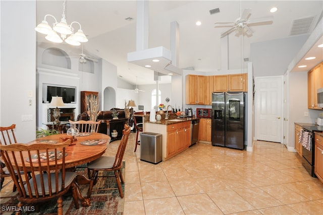 kitchen with high vaulted ceiling, ceiling fan with notable chandelier, dark stone countertops, appliances with stainless steel finishes, and kitchen peninsula