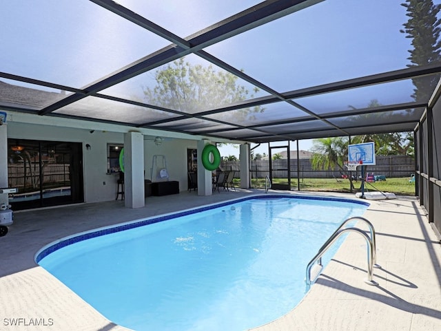 view of swimming pool featuring glass enclosure, ceiling fan, and a patio