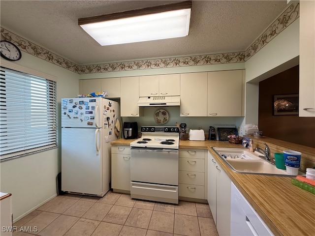 kitchen with white appliances, sink, a textured ceiling, and light tile patterned floors