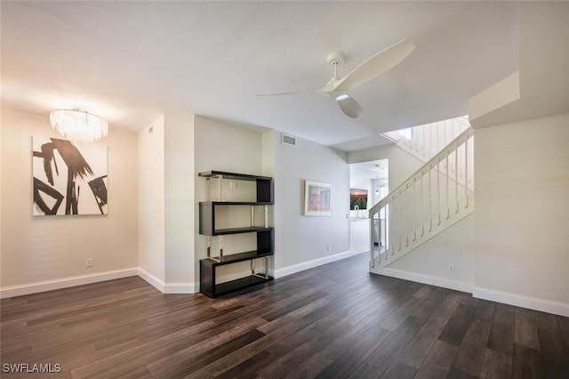 unfurnished living room with dark hardwood / wood-style flooring and ceiling fan with notable chandelier