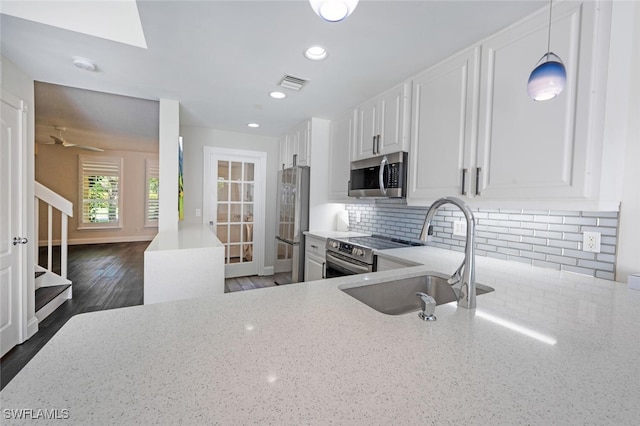 kitchen with white cabinets, sink, decorative backsplash, appliances with stainless steel finishes, and decorative light fixtures