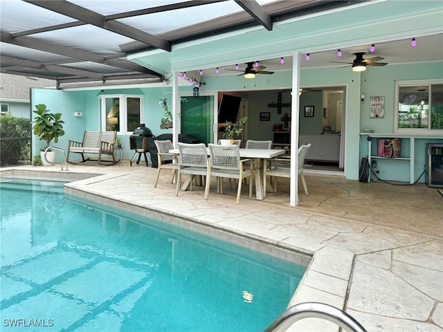 view of pool with ceiling fan, glass enclosure, and a patio area