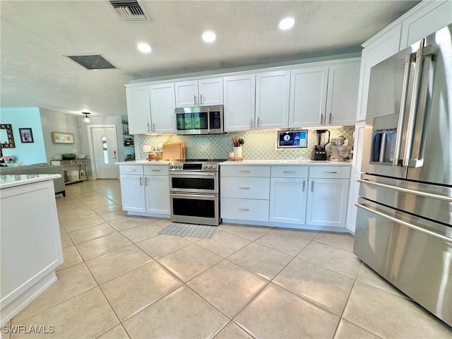 kitchen featuring appliances with stainless steel finishes, white cabinets, tasteful backsplash, and light tile patterned flooring