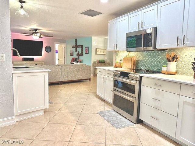 kitchen with backsplash, white cabinets, stainless steel appliances, and light tile patterned floors