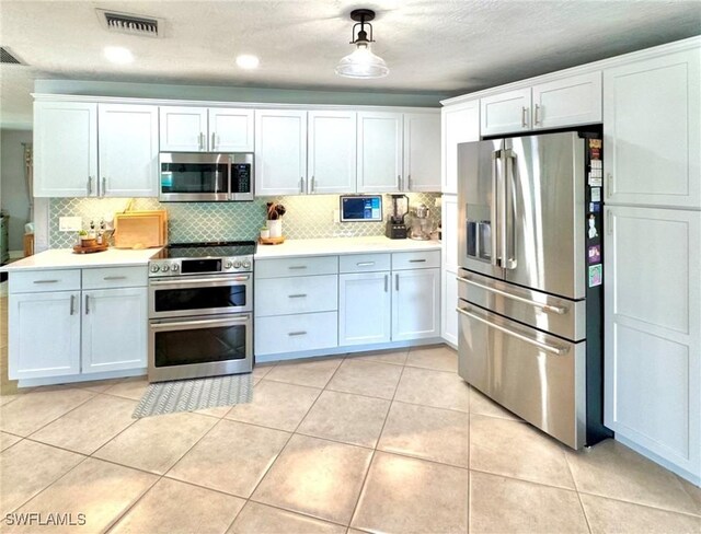 kitchen with appliances with stainless steel finishes, white cabinets, and hanging light fixtures