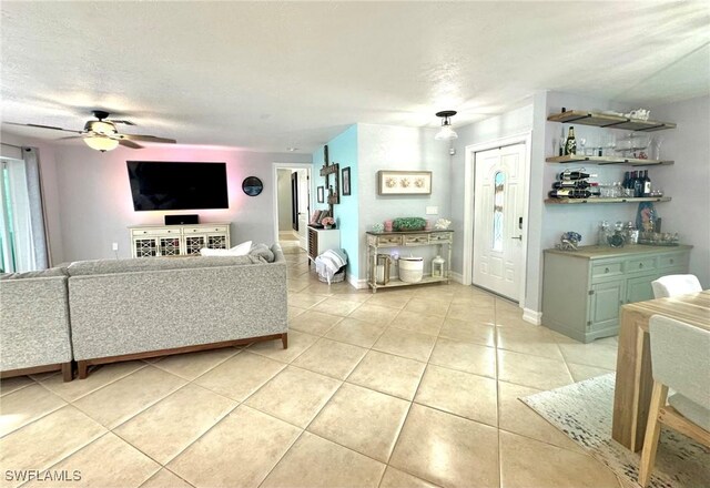 living room featuring light tile patterned floors, ceiling fan, and a textured ceiling