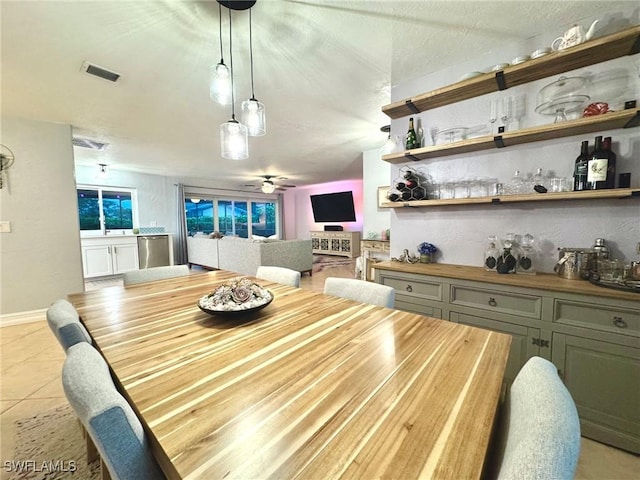 dining room with light tile patterned floors, ceiling fan, and indoor bar