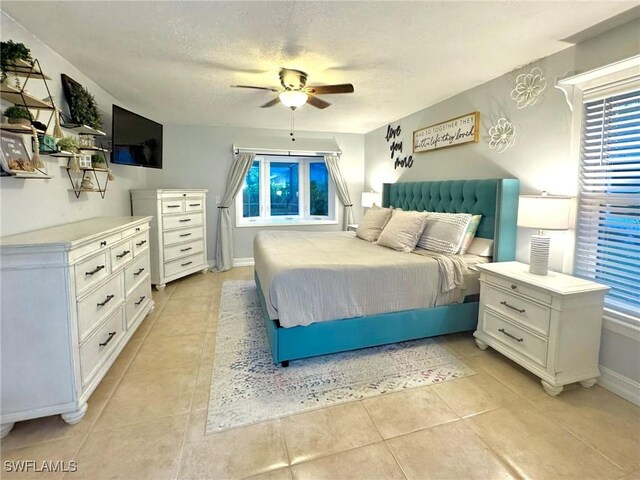 bedroom with light tile patterned flooring, ceiling fan, and a textured ceiling