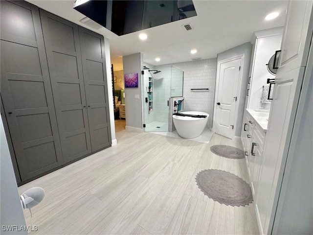 bathroom featuring hardwood / wood-style floors, separate shower and tub, and vanity