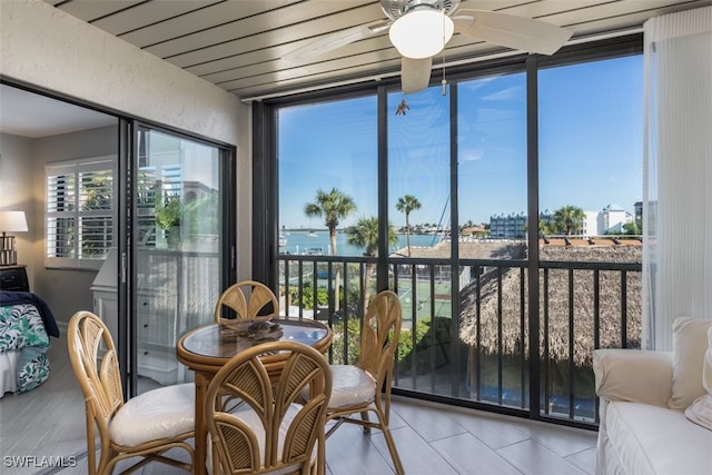 sunroom with ceiling fan and a water view