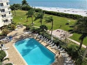 view of swimming pool with a water view and a view of the beach