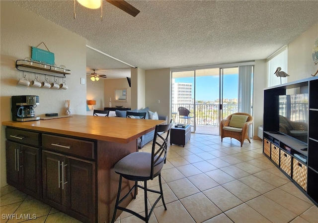 kitchen featuring a kitchen breakfast bar, ceiling fan, expansive windows, and a textured ceiling