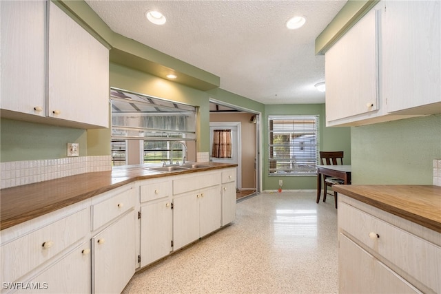 kitchen with a textured ceiling, white cabinetry, a healthy amount of sunlight, and sink